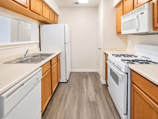 A kitchen with white appliances and wooden cabinets.