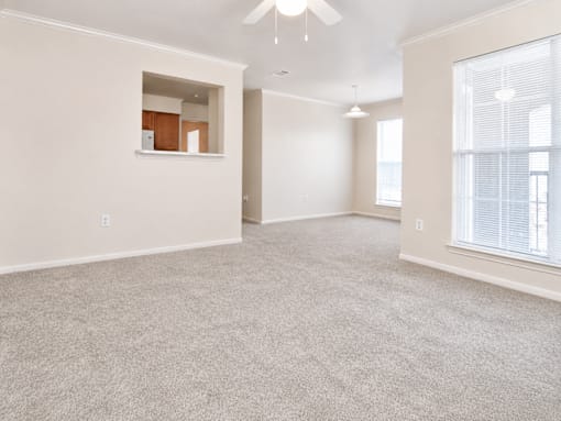 A spacious room with a window and a ceiling fan.