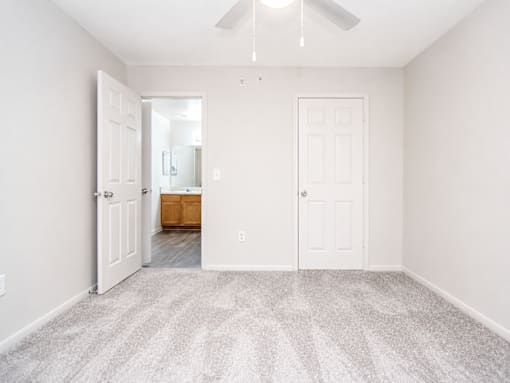 A room with a carpeted floor and a ceiling fan.