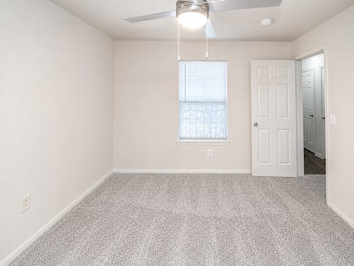 A room with a ceiling fan and a window with blinds.
