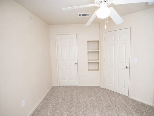 A room with a ceiling fan and two doors.