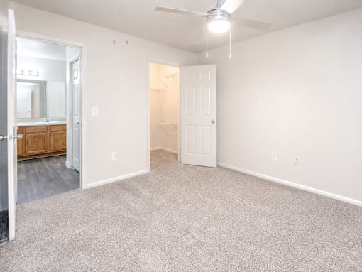 A room with a carpeted floor and a ceiling fan.