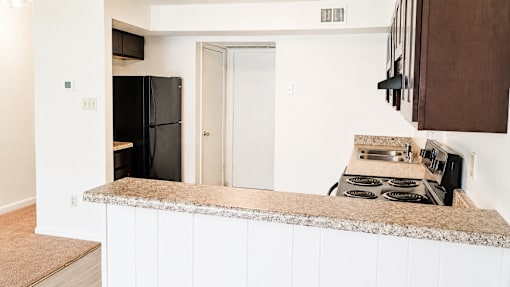 A kitchen with a black fridge and stove top oven.
