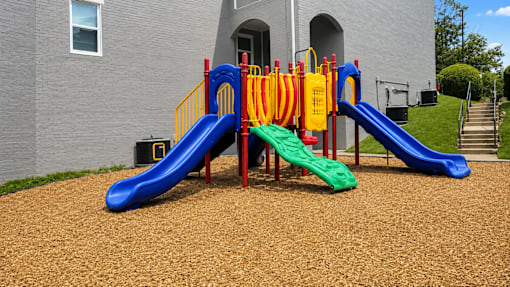 A playground with a blue slide and a green slide.