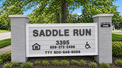 A sign for Saddle Run with contact information and a direction to the leasing office.