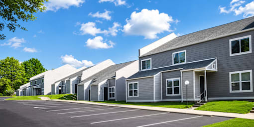 A row of modern houses with grey exteriors and white roofs.
