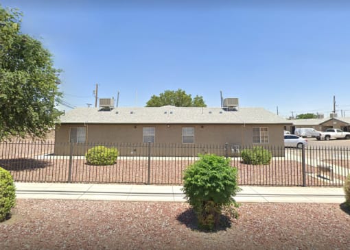 the front of a house with a fence and a parking lot