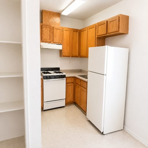 A kitchen with white appliances and wooden cabinets.