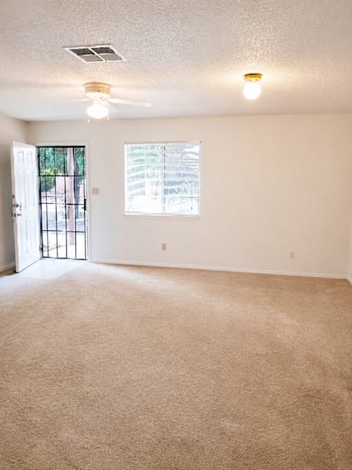A room with a carpeted floor and a ceiling fan.