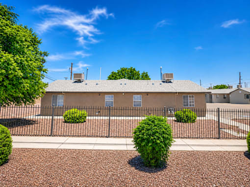 A building with a black fence and bushes in front.