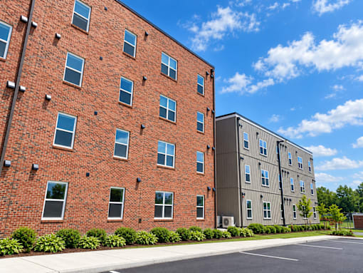 A red brick building with a parking lot in front.