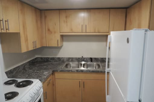 A kitchen with a white stove, wooden cabinets, and a white refrigerator.