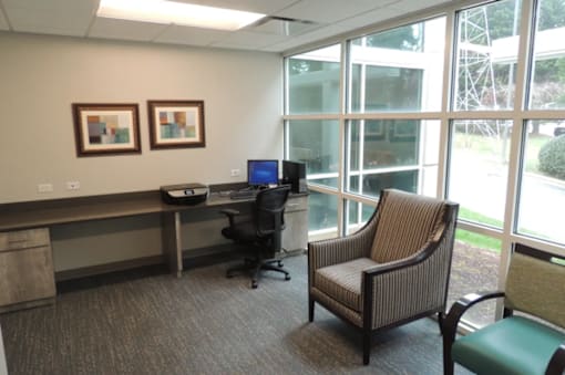 A room with a desk, chair, and two pictures on the wall.