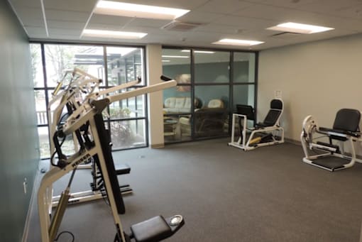 A gym room with a weight machine, a bench, and a chair.
