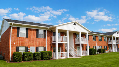A red brick apartment building with white trim and a white porch.