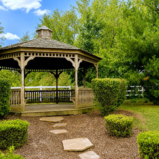 A wooden gazebo with a stone pathway leading to it.