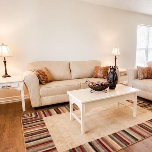 A living room with a white couch, a white coffee table, and a striped rug.