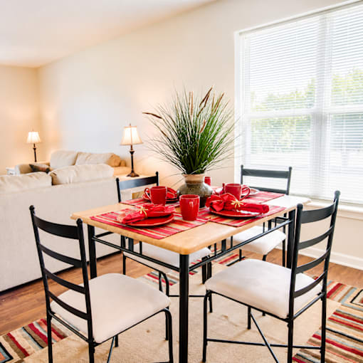 A dining table set with red napkins and plates is surrounded by chairs.