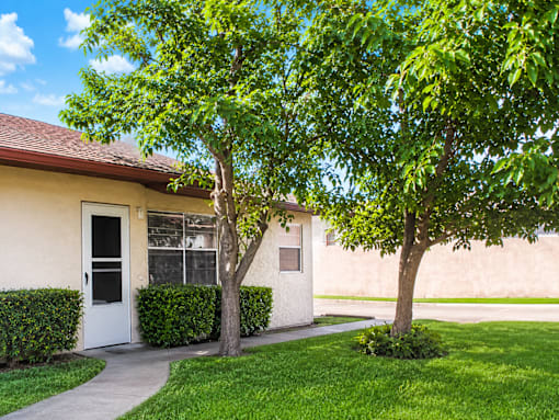 A house with a white door and a tree in front.