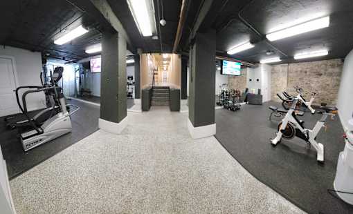 A gym with a variety of exercise equipment including treadmills, stationary bikes, and weights.