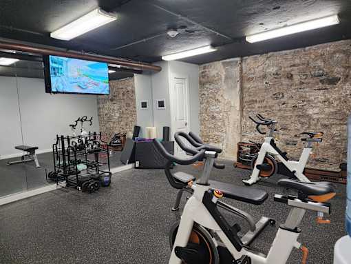 A gym with exercise bikes and a television screen.