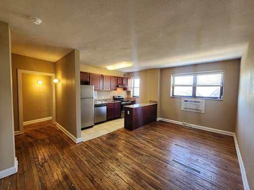 A kitchen with wooden floors and a refrigerator.