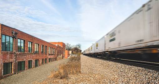 A train is passing by a row of red brick buildings.