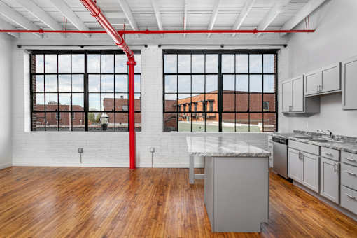 A kitchen with a large island and a red pipe running along the ceiling.