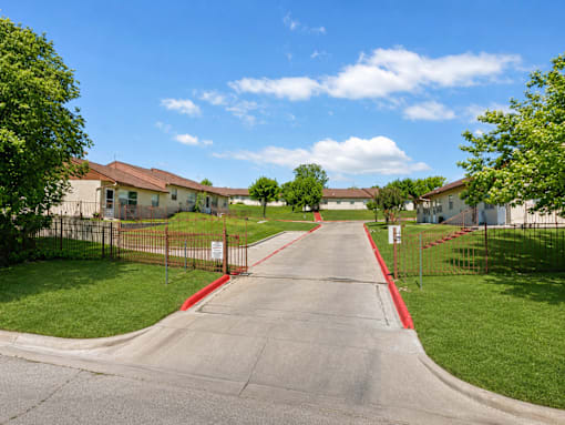 A residential street with houses on both sides and a red curb.