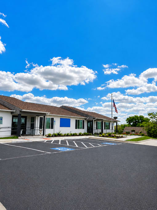 A building with a flag on the right side and a parking lot in front.