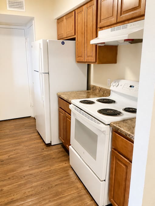 A white refrigerator and oven in a kitchen with wooden cabinets.