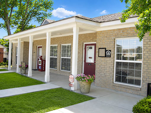 A house with a red door and a sign that says "For Sale".