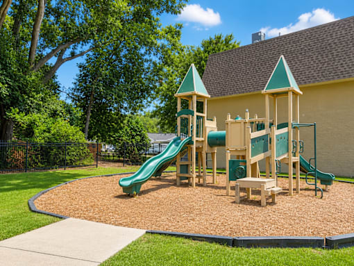 A playground with a green slide and wooden structure.