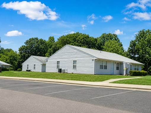 A white building with a grey roof is surrounded by a parking lot.