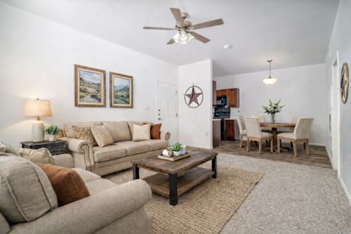 A living room with a beige couch, a coffee table, and a ceiling fan.