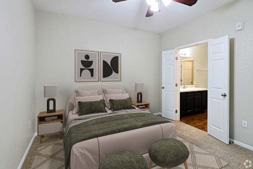 A bedroom with a bed, two lamps, and two framed pictures on the wall.