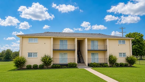 A large two-story apartment building with a lawn in front.