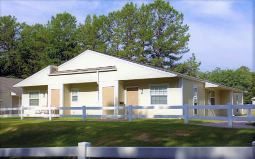 the front of a white house with a white fence