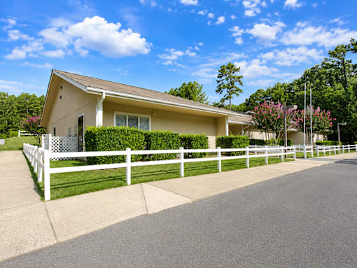 A house with a white fence and a driveway in front.