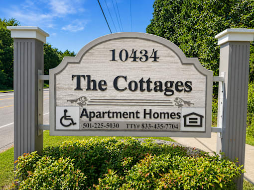 A sign for The Cottages Apartment Homes with a phone number and TTY number.