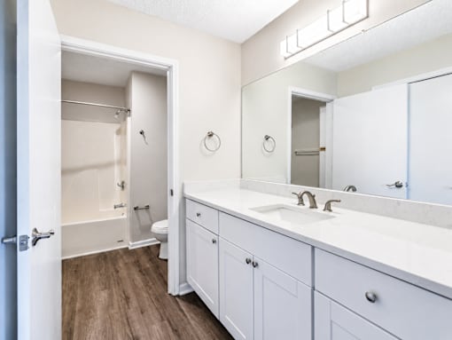 A white bathroom with a toilet, sink, and mirror.