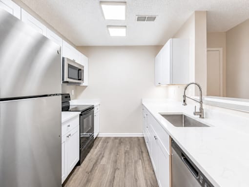 A kitchen with white cabinets and a stainless steel refrigerator.