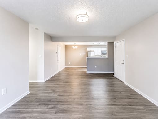 A spacious room with wooden flooring and white walls.