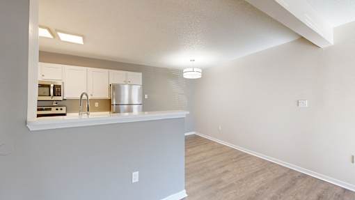 A kitchen with white cabinets and a wooden floor.