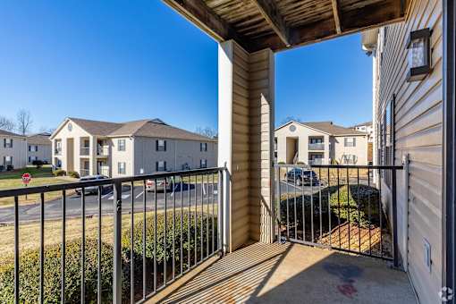 A view from a balcony looking out at a residential area with houses and a clear blue sky.