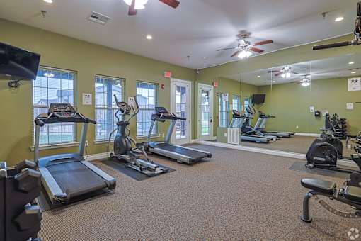A gym with treadmills, elliptical machines, and other exercise equipment.