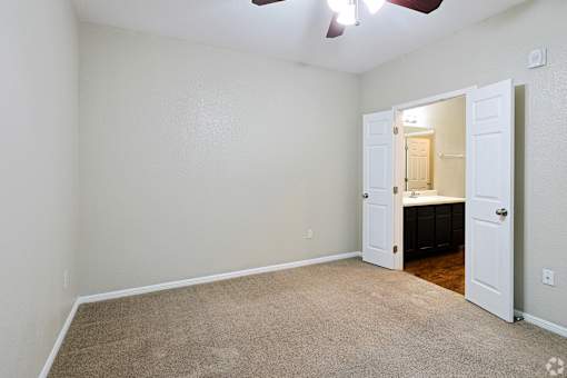 A room with a carpeted floor and a ceiling fan.