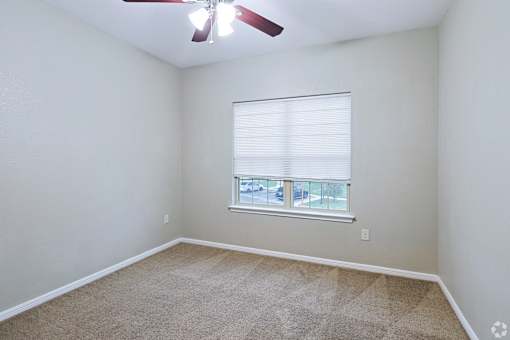 A room with a ceiling fan and a window with blinds.