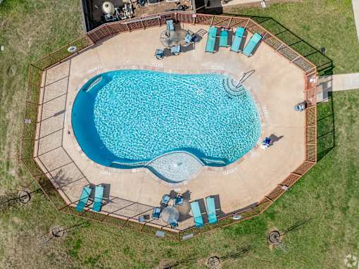 An aerial view of a swimming pool surrounded by a fence and lounge chairs.