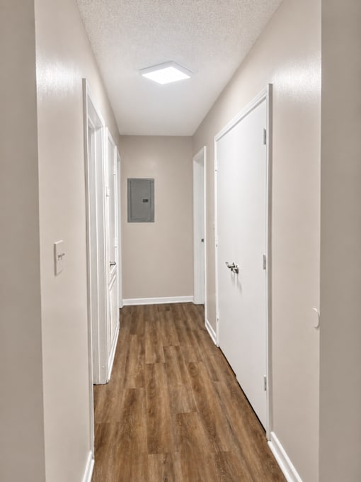 A long hallway with white doors and wood floors.